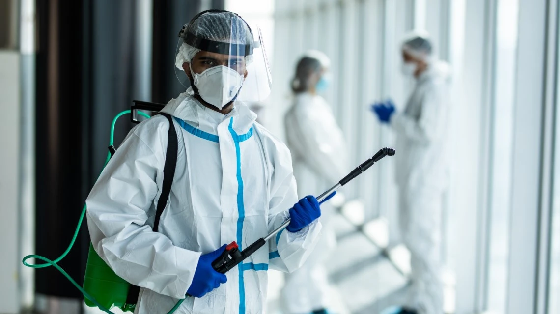 Técnico de desinfeção com fato de proteção com equipamento em ambiente hospitalar.